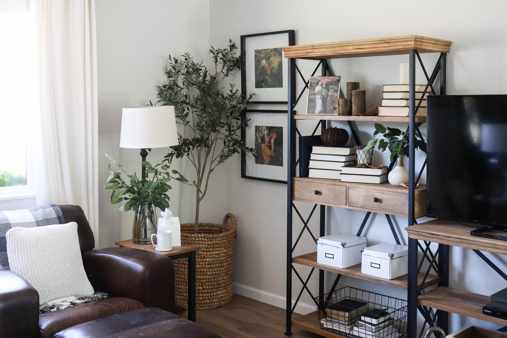 A picture of a living room with open wood shelves and pictures on the wall.