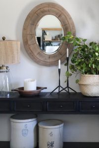 A picture of a black console table and wood mirror.