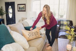 A picture showing a pillow being placed on the couch.