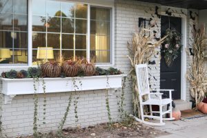 A picture of the front of a house with a white window box, pumpkins, and black bats.
