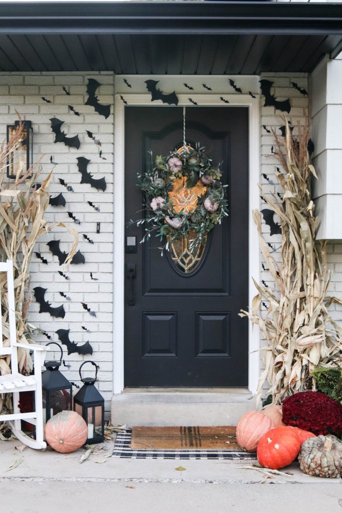 A picture of a front porch with black bats hanging from the siding. 