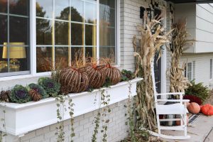 A picture of a large window box with wicker pumpkins and flowering kale with ivy coming over the sides.