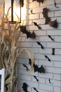 A picture of black bats on the side of a cream house.