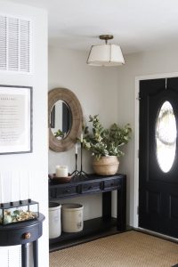 A picture of an entry with a black front door and console table.