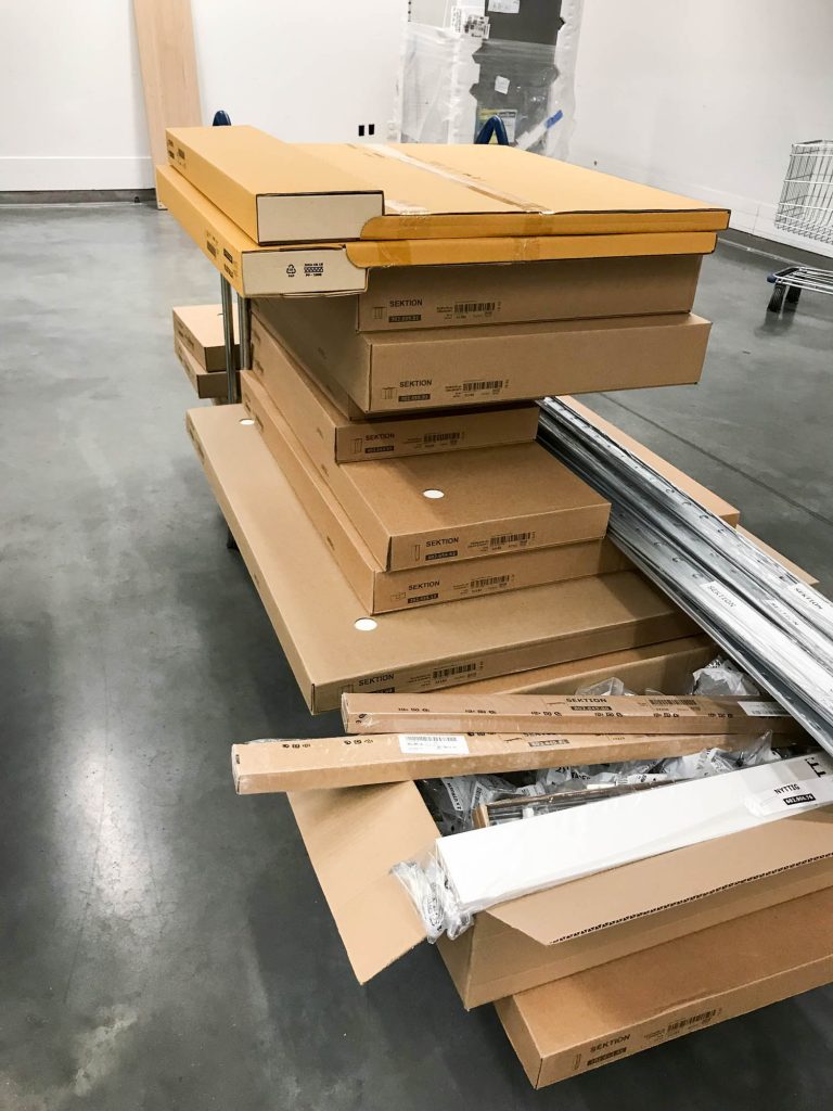 A picture of an Ikea cart filled with cabinet boxes.
