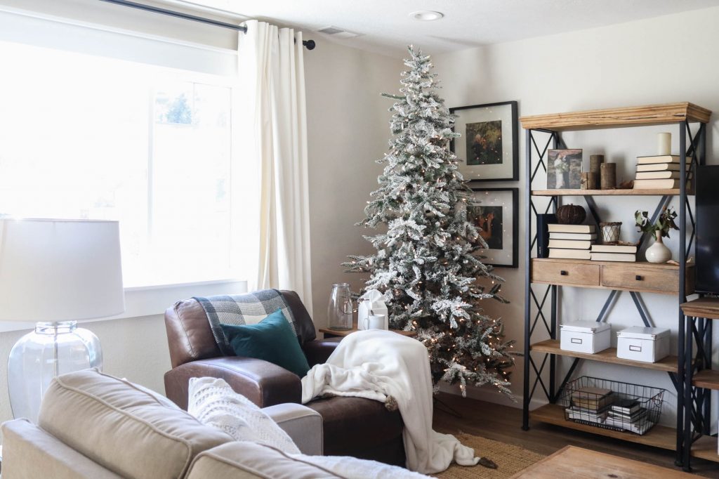 A picture of a living room with a flocked Christmas tree.