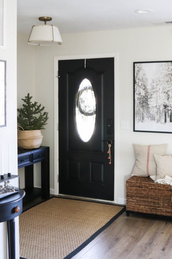 A picture of an entry way with a black door and winter wonderland print. 