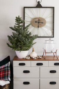 A picture of a dresser with a clock and mini Christmas tree.