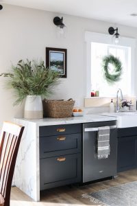A picture of a kitchen with a wreath hanging in the window.