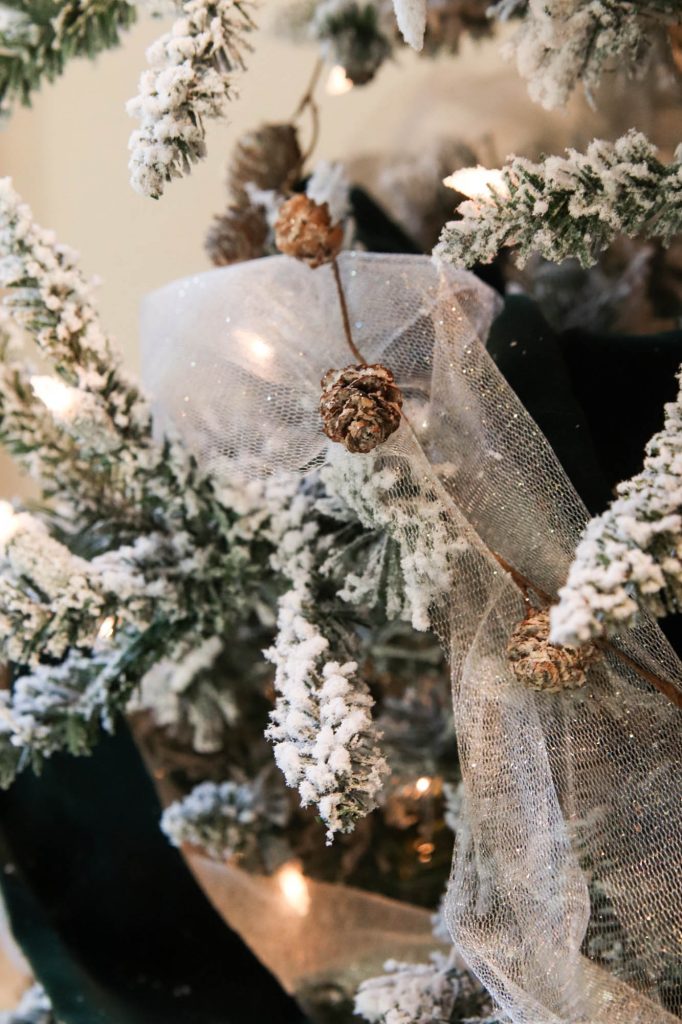 A picture of a flocked Christmas tree with pinecone garland.