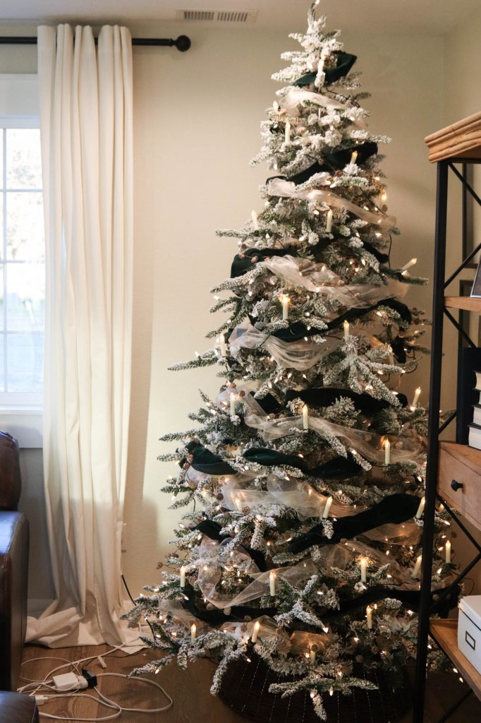 A picture of a flocked Christmas tree with candle lights and garland.