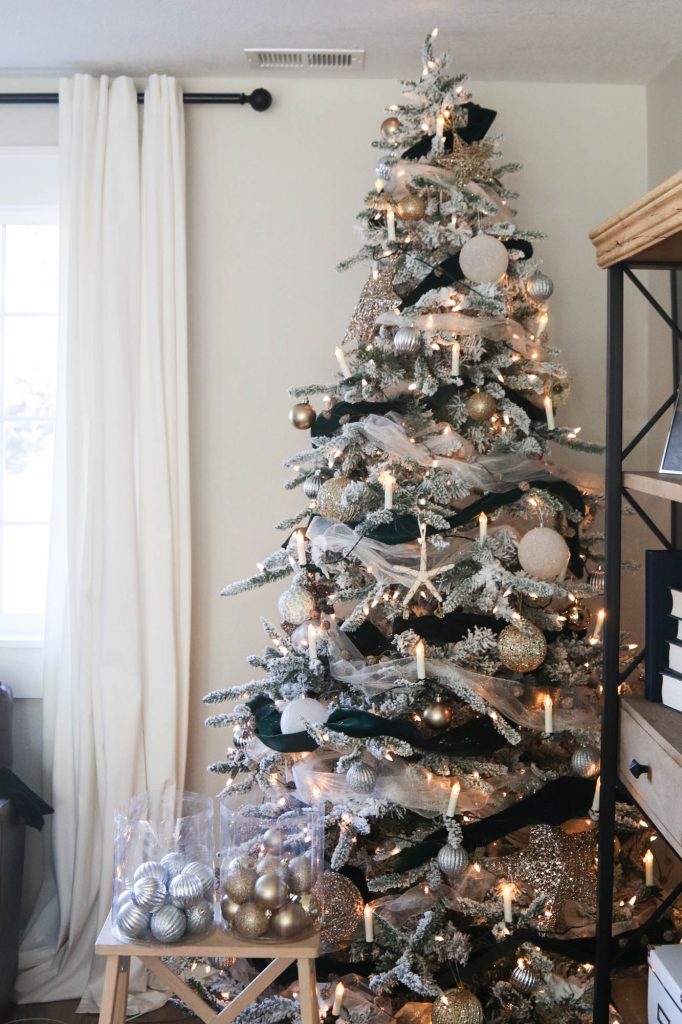 A picture of a flocked Christmas tree being decorating.