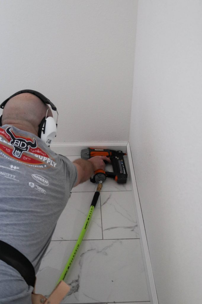 A picture of Todd installing the baseboard trim. 
