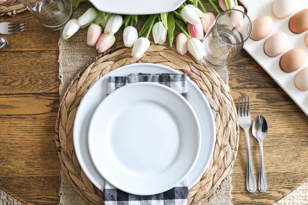 A picture of a table set for easter with white dinnerware. 