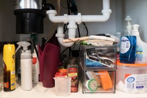 A picture showing the cabinet before organizing under the kitchen sink.