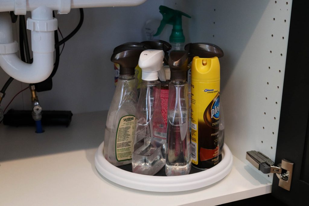 A picture showing the third step of organizing under the kitchen sink: using a turntable for bottles of cleaning supplies. 