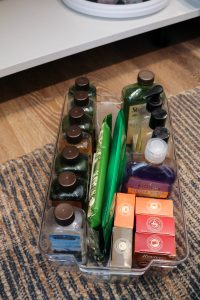 A picture showing the first step of organizing under the kitchen sink: organizing some bulk cleaning supplies in an acrylic tote.