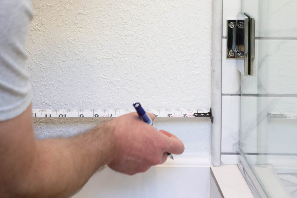 A picture of Todd measuring over 3" from the shower tile.