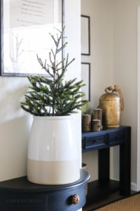 A picture of a small, faux tree in a ceramic vase.