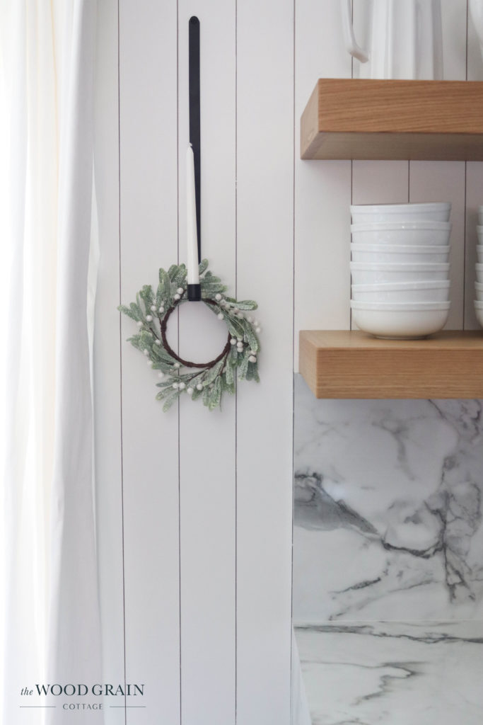 A picture of a faux wreath hanging on a candlestick. 